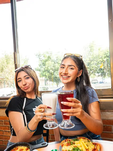 Dos clientas brindando junto a la ventana