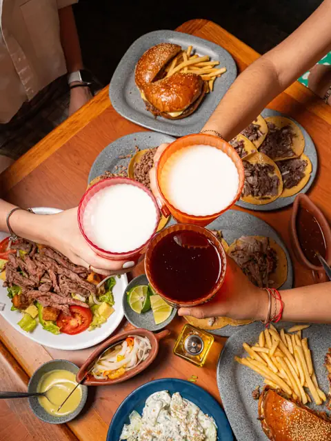Brindis con cervezas sobre una mesa llena de comida