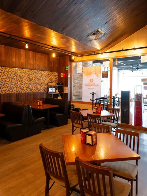 Comedor de La Vecindad con mesas de madera y luz cálida