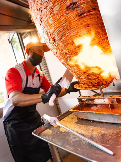El taquero cortando la carne del trompo