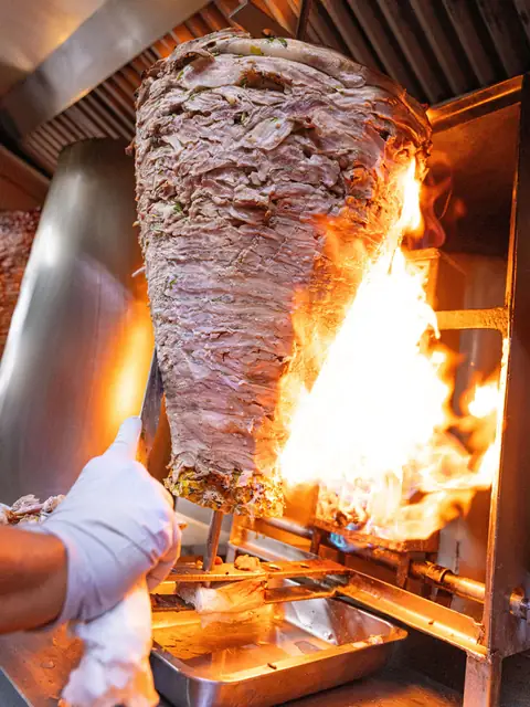 Trompo al pastor girando junto a la llama del asador